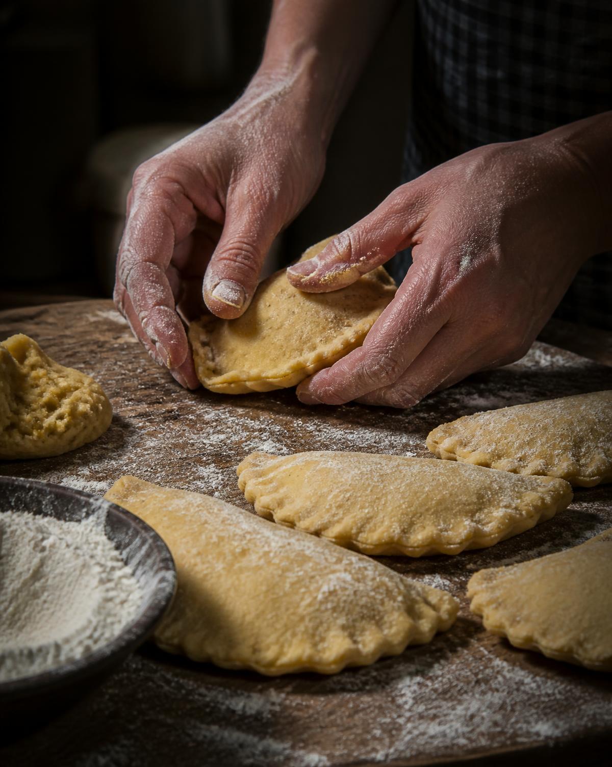 Hands shaping corn dough for handmade Colombian empanadas in Nassau, Bahamas